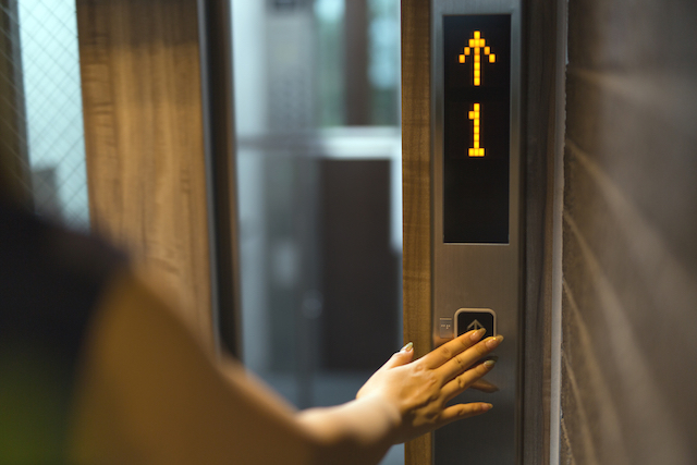 エレベーターのボタンを押す女性